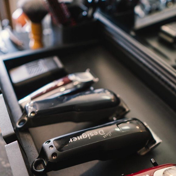 Máquinas de corte enfileiradas na bancada, ao lado do pincel de barba.