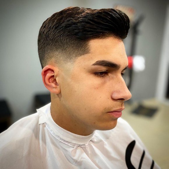 Corte com topete alto e degradê fechado nas laterais, visto de perfil.